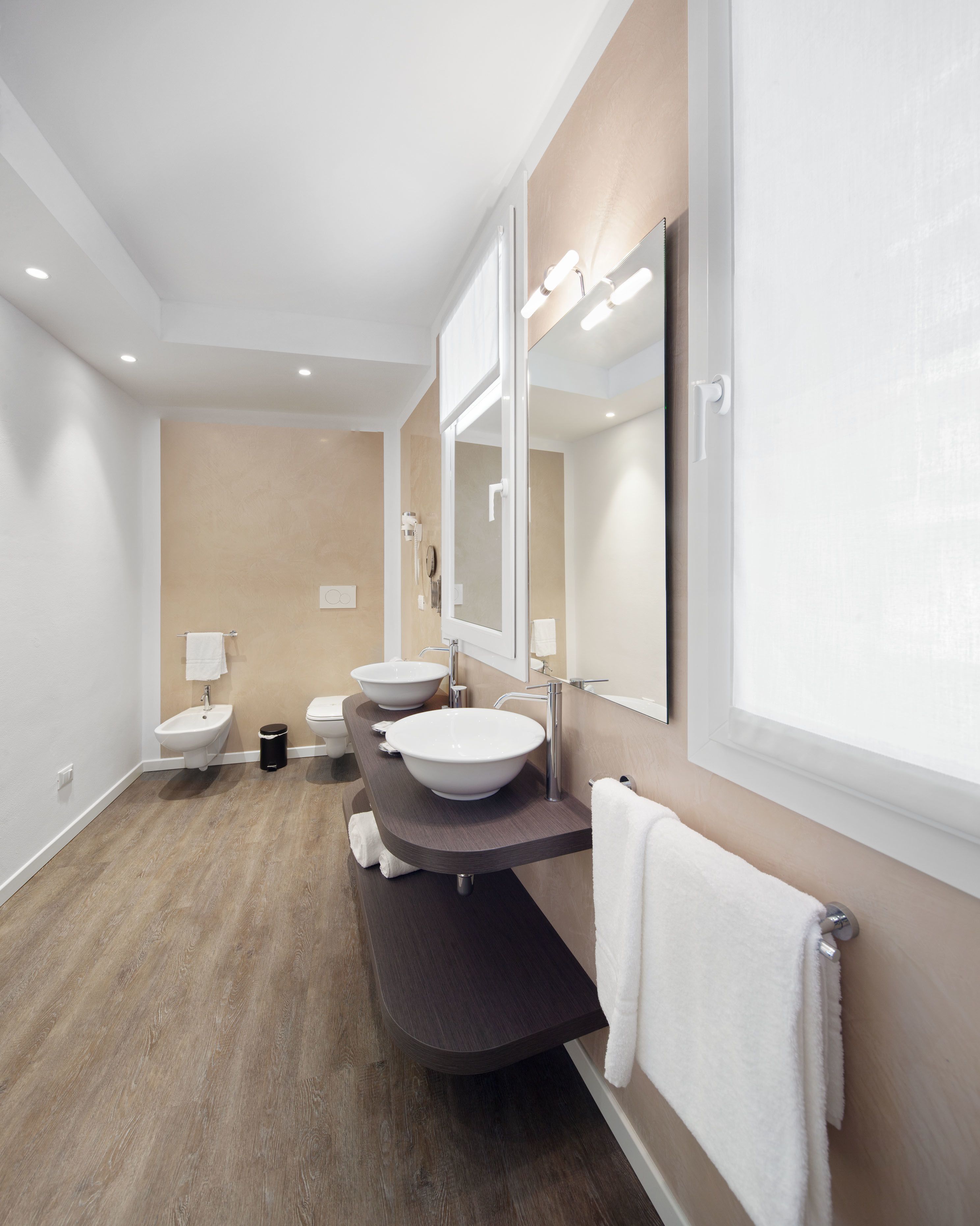 Un baño moderno con dos lavamanos, un inodoro y un bidé.