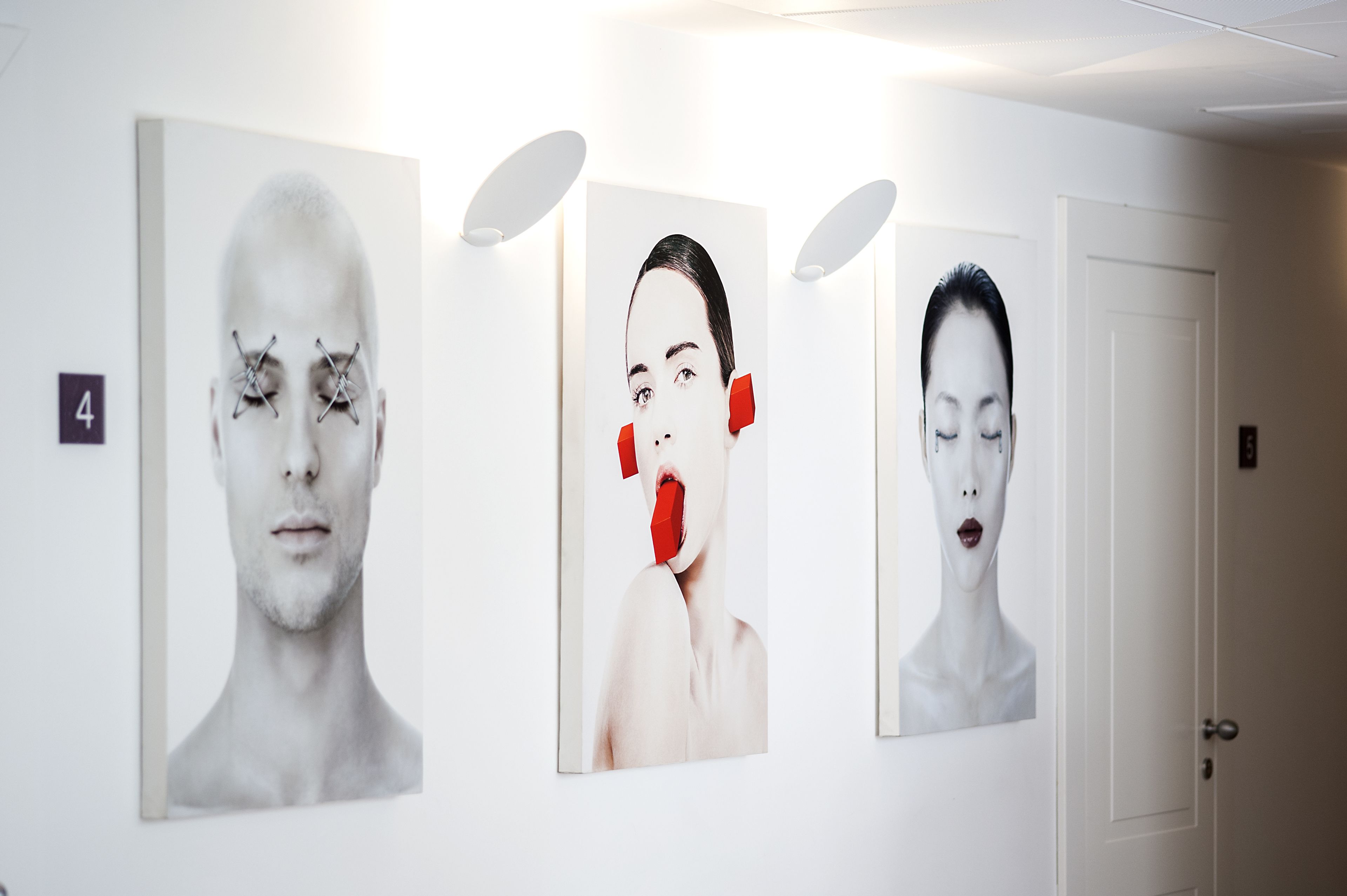 Tres retratos enmarcados en una pared, con una puerta al fondo.
