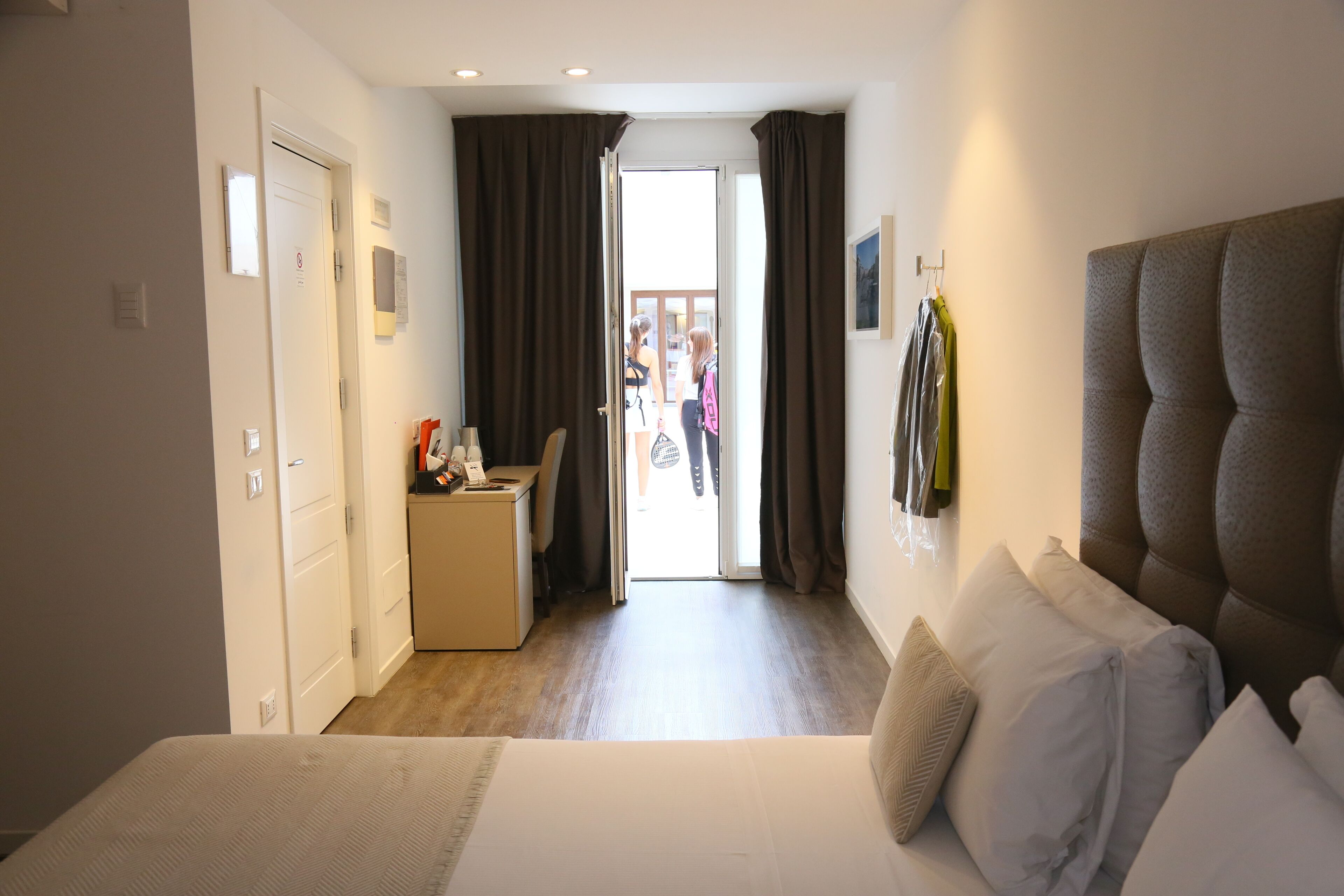 Una habitación de hotel con cama, escritorio y vista a través de una puerta abierta.