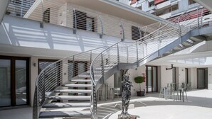 A modern building with a central spiral staircase, multiple balconies, and a courtyard with outdoor seating. - Hotel Studio Inn Centrale & Milano Urban Padel (Milan)