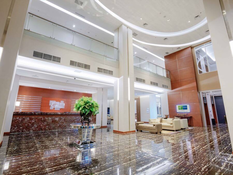 A spacious lobby with a reception desk, seating area, and a large plant centerpiece.