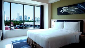 A hotel room with a large bed, a view of the city, and a painting on the wall. - Holiday Inn Express Jakarta International Expo by IHG (Jakarta)