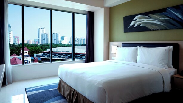 A hotel room with a large bed, a view of the city, and a painting on the wall. - Holiday Inn Express Jakarta International Expo by IHG (Jakarta)