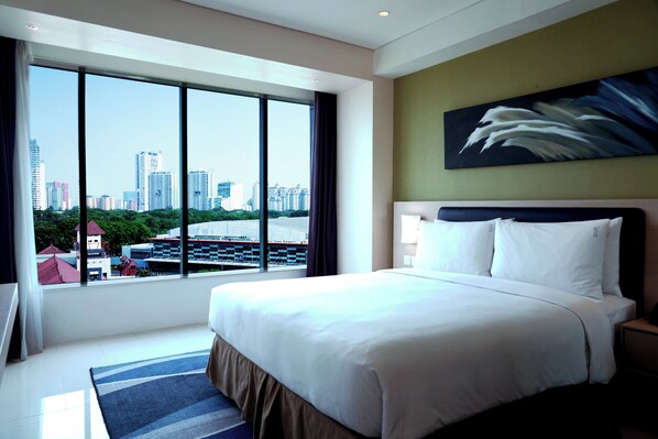A hotel room with a large bed, a view of the city, and a painting on the wall. - Holiday Inn Express Jakarta International Expo by IHG (Jakarta)