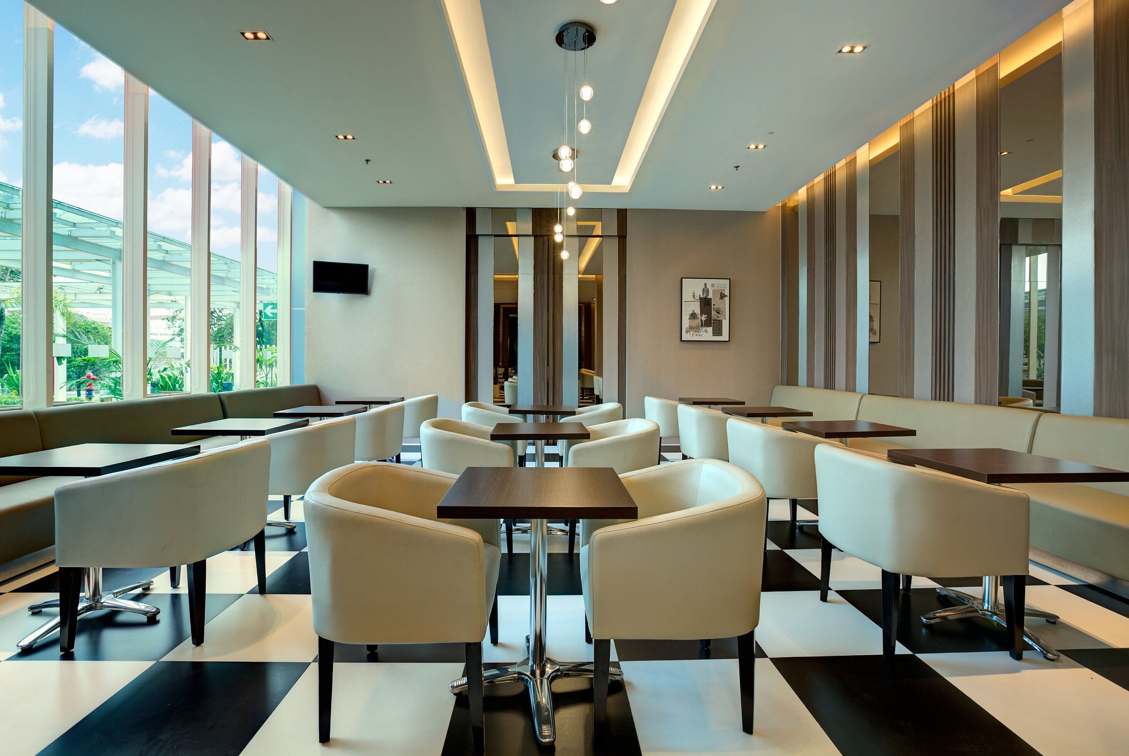 A modern restaurant with high ceilings, large windows, and a checkered floor.
