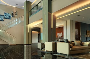 A modern lobby with a glass staircase, a seating area with sofas and a coffee table, and a reception desk. - Holiday Inn Express Jakarta International Expo by IHG (Jakarta)