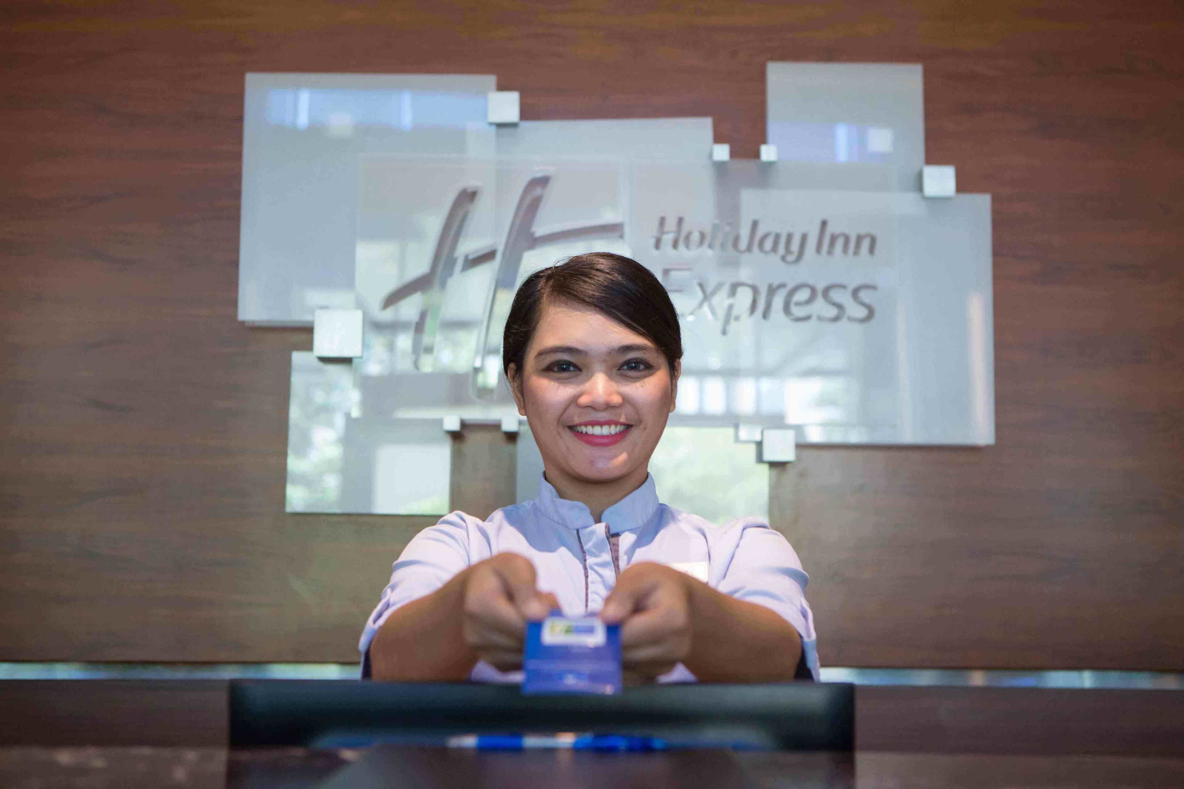 Una persona sentada en la recepción, con un cartel de Holiday Inn Express al fondo.