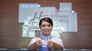 A person seated at a reception desk with a Holiday Inn Express sign in the background. - Holiday Inn Express Jakarta International Expo by IHG (Jakarta)