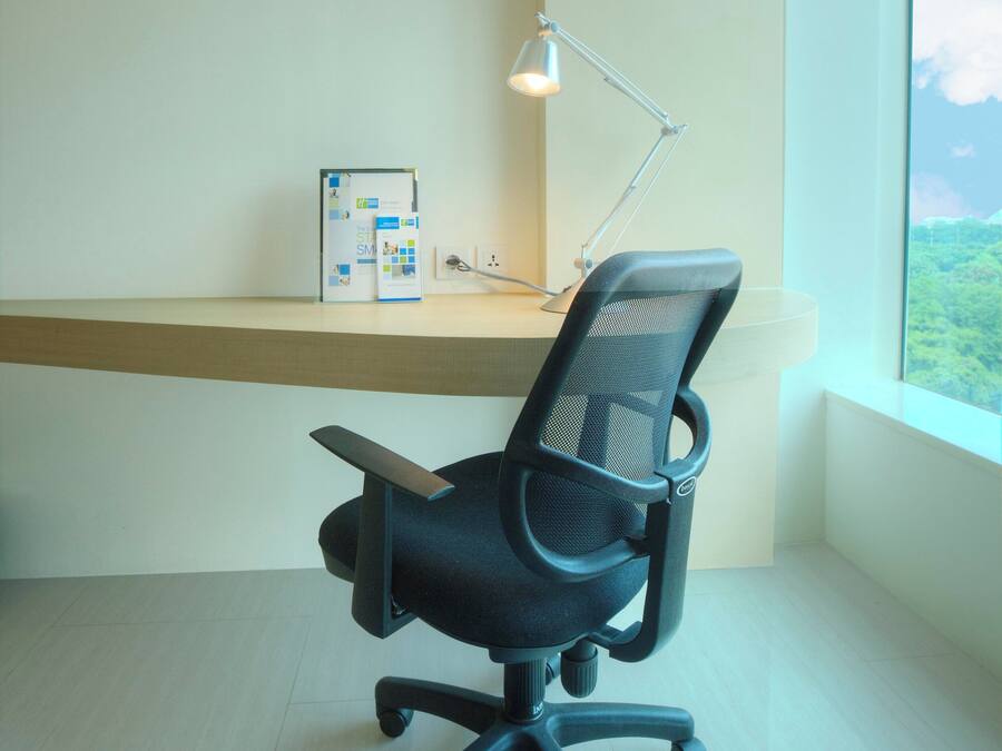 A workspace with a desk, chair, lamp, and a window with a view.