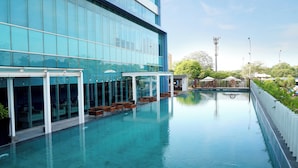 A modern hotel with a swimming pool, glass facade, and outdoor seating area. - Holiday Inn Express Jakarta International Expo by IHG (Jakarta)
