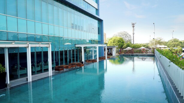 A modern hotel with a swimming pool, glass facade, and outdoor seating area. - Holiday Inn Express Jakarta International Expo by IHG (Jakarta)