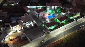 An aerial view of a residential area with houses, a swimming pool, and a street. - Pousada Luak (Lagoa Santa)