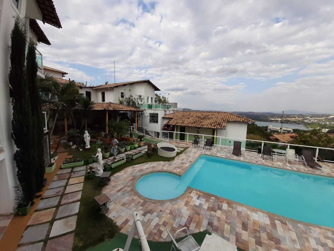 A swimming pool with a tiled deck, surrounded by potted plants and outdoor furniture.