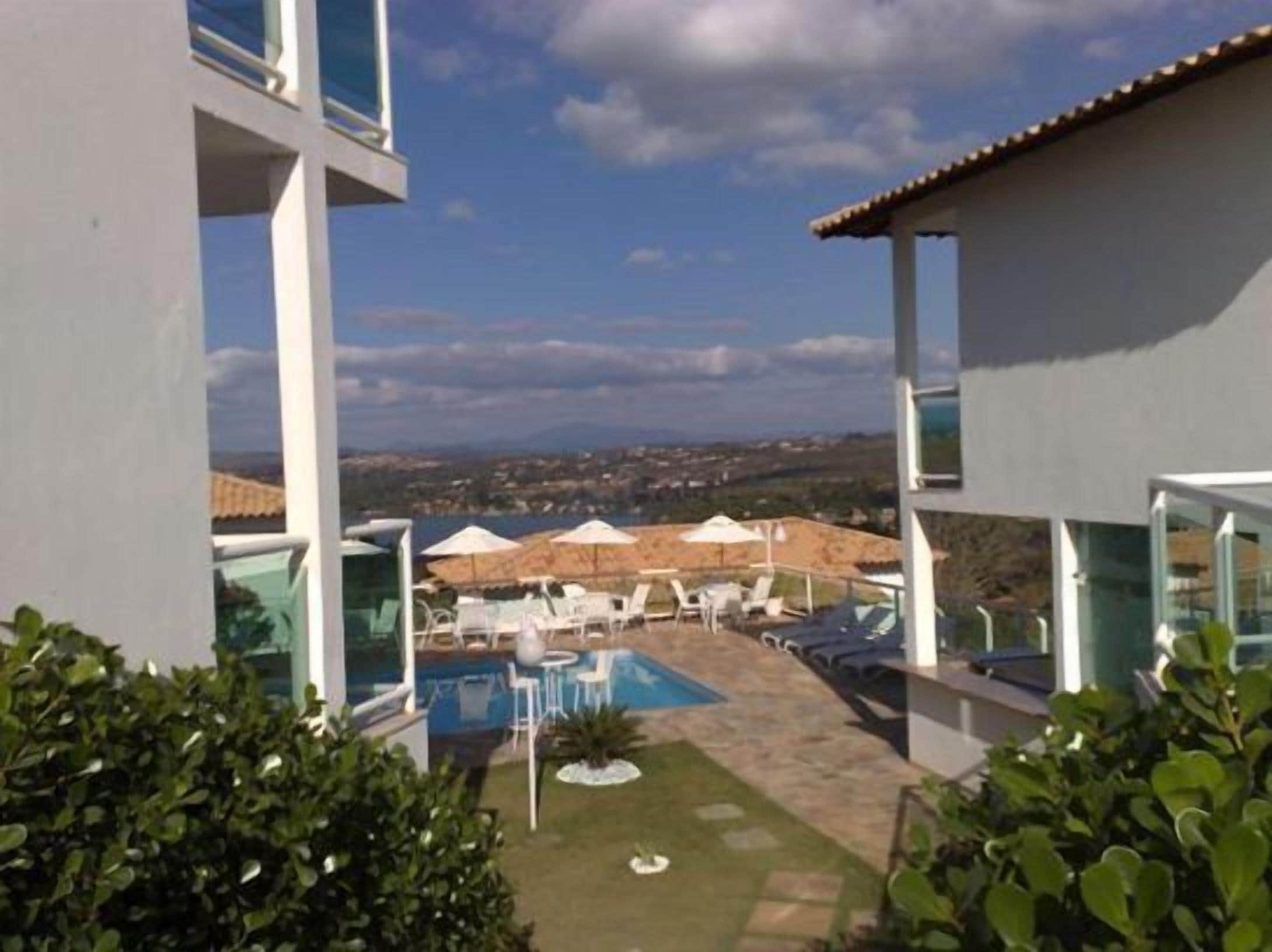 Un edificio moderno con zona de piscina, mobiliario exterior y vistas a la ciudad.