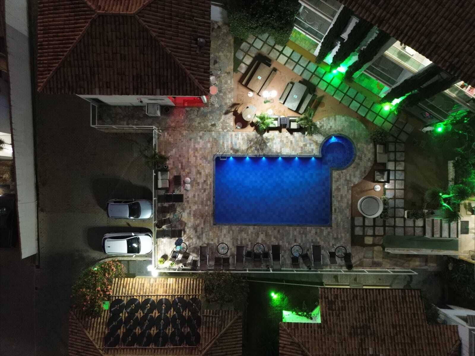 An aerial view of a rooftop pool area with a swimming pool, lounge chairs, and a covered seating area.