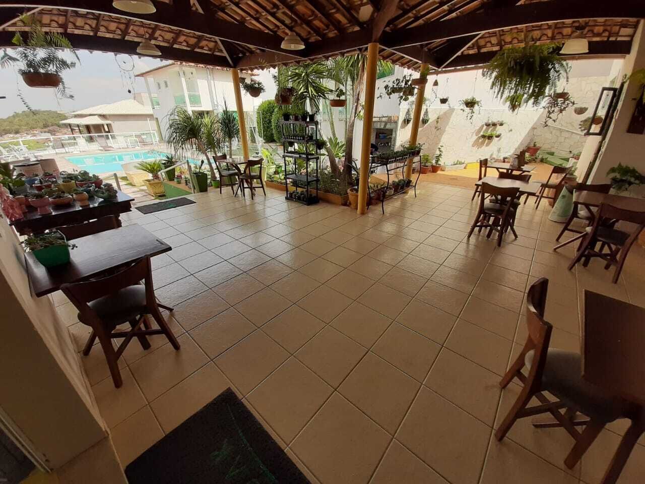 A covered outdoor patio with tiled flooring, wooden furniture, and hanging plants.