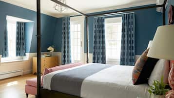 Un dormitorio con cama con dosel, una mesita de noche con lámpara, un aparador y una ventana con cortinas.