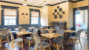 A restaurant with wicker chairs, wooden tables, and a blue cushioned bench. - The Christopher, The Edgartown Collection (Edgartown)