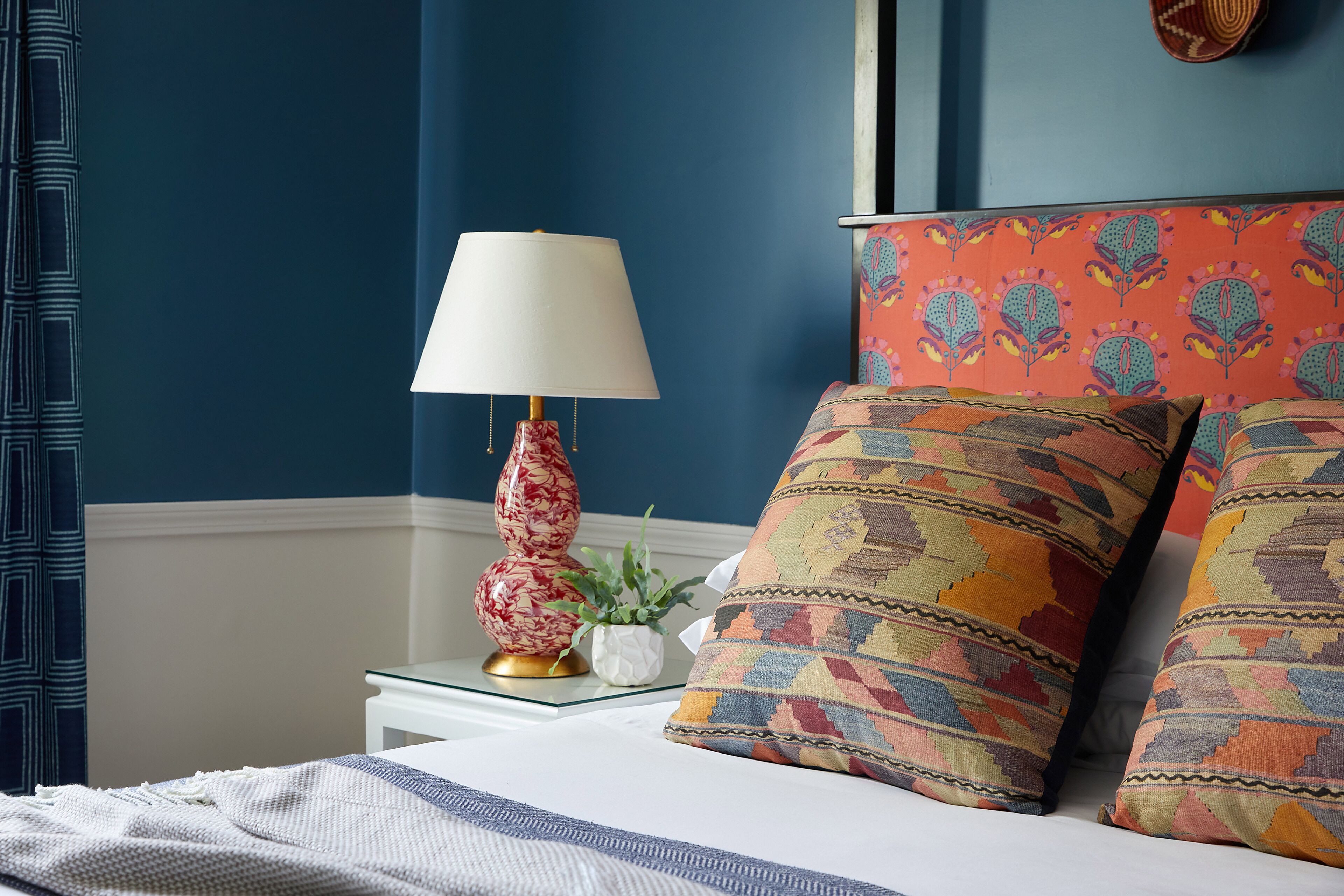 A bedroom with a bed, a nightstand, a lamp, and patterned pillows.