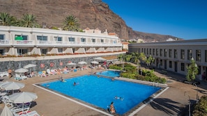 Een buitenzwembad, parasols bij het zwembad en ligstoelen