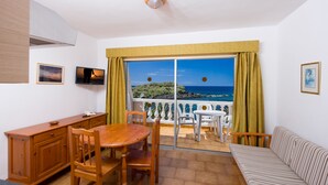 A room with a dining table, chairs, a sofa, a kitchen area, and a balcony with a view of the sea. - Charco del Conde (Valle Gran Rey)