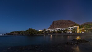 A coastal hotel with a mountain backdrop, calm waters, and a clear night sky. - Charco del Conde (Valle Gran Rey)