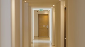 A long, narrow hotel corridor with a wooden door at the end, marked with the number 303.