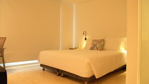 A modern hotel room with a large bed, a bedside table, and a nightstand.