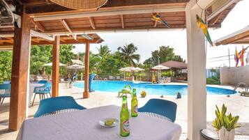 Un espace aménagé au bord de la piscine, avec une table, des chaises et une bouteille de bière.