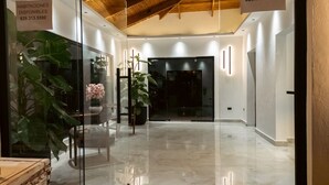 Decoração moderna com divisória de vidro, plantas em vasos e placa indicando acomodações disponíveis.
