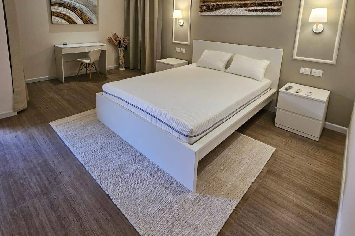 A modern bedroom with a large bed, bedside tables, a desk, and artwork on the walls.
