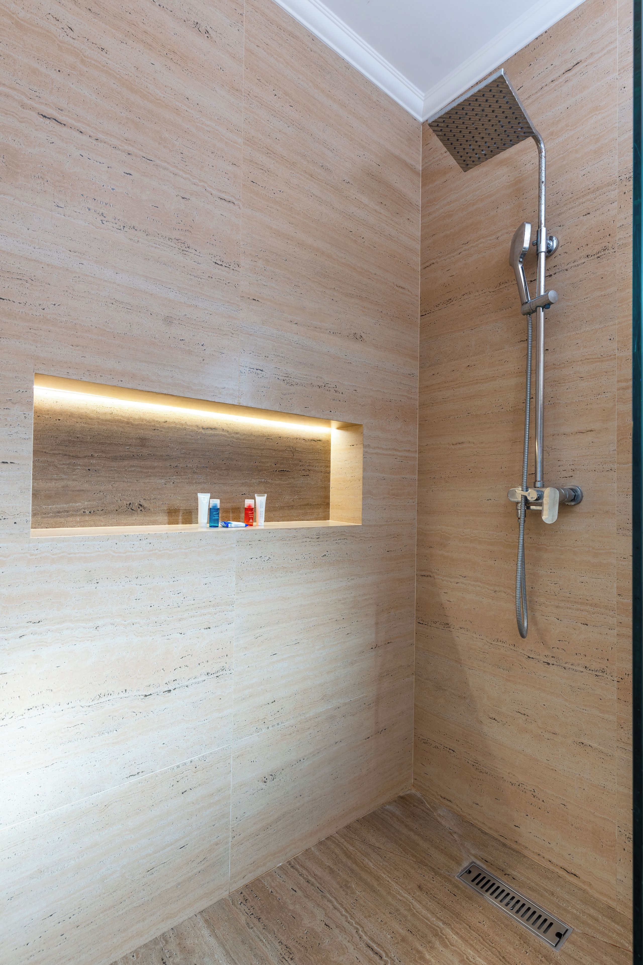 A modern shower area with a built-in shelf for toiletries.