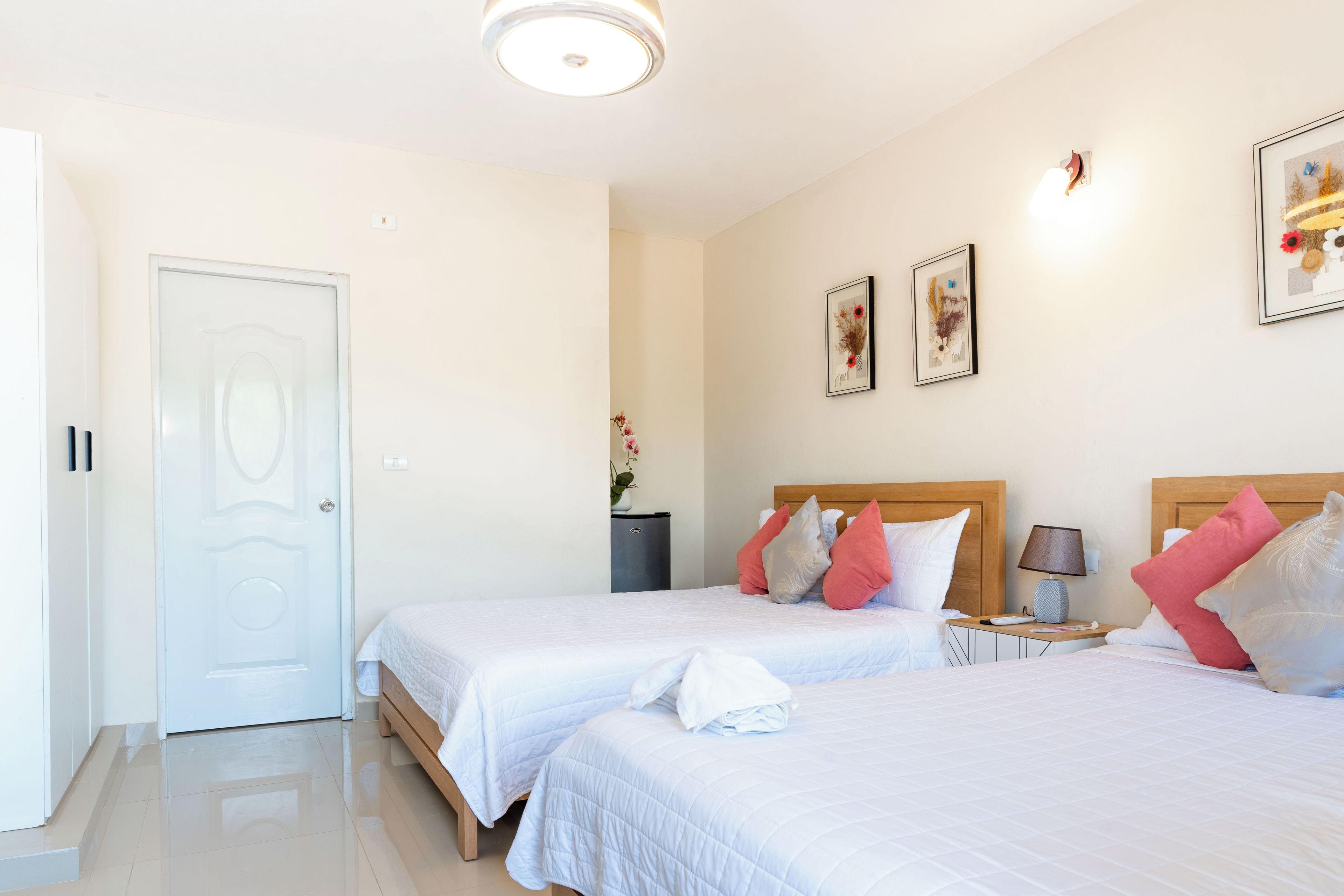 Une chambre d’hôtel avec deux lits, une table de chevet, une lampe et une porte.