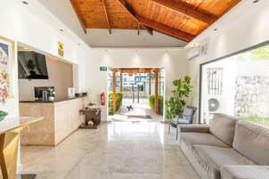 Vestíbulo de hotel con mostrador de recepción, un sofá y vistas al exterior.