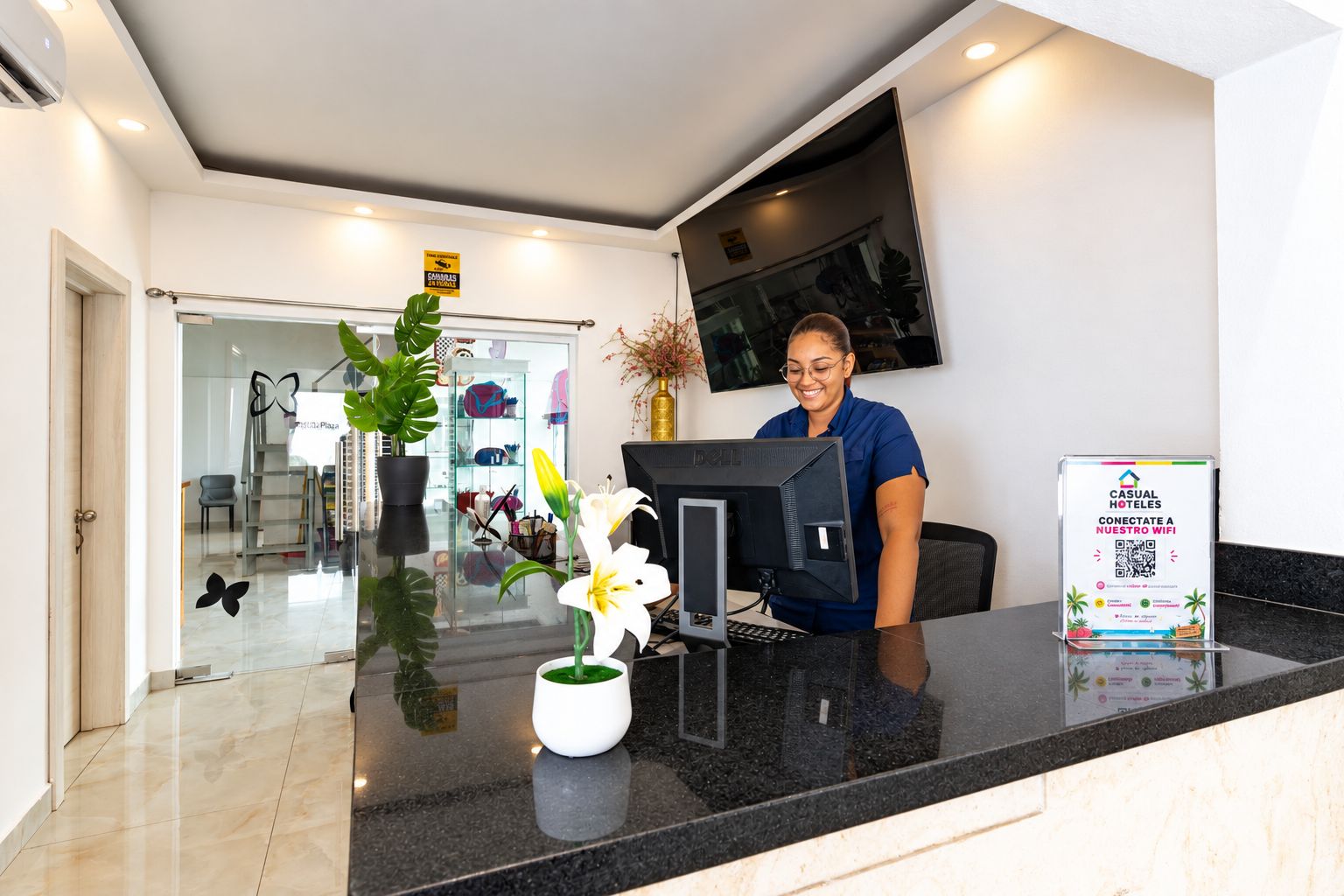 A reception desk with a computer, a sign about WiFi, and a plant.