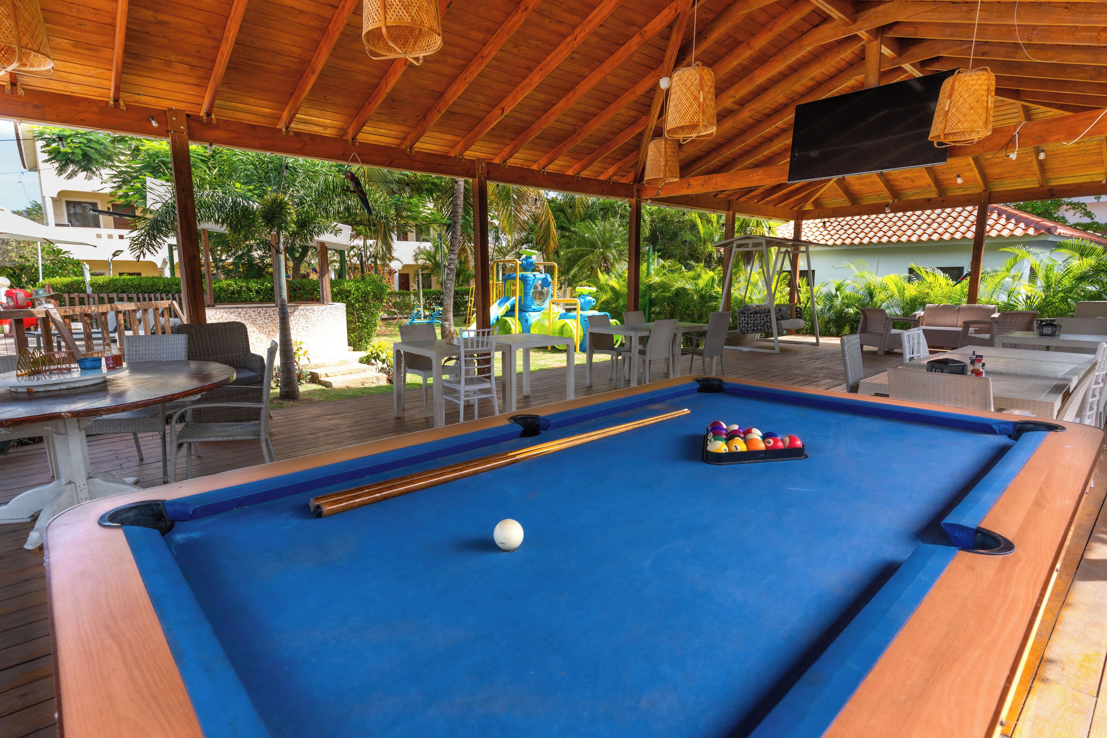 An outdoor pool area with a blue pool table, lounge chairs, and a children's play area.