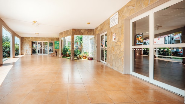 Un vestíbulo amplio con pared de piedra y puertas de cristal que dan al exterior.