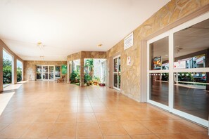 Un vestíbulo amplio con pared de piedra y puertas de cristal que dan al exterior.