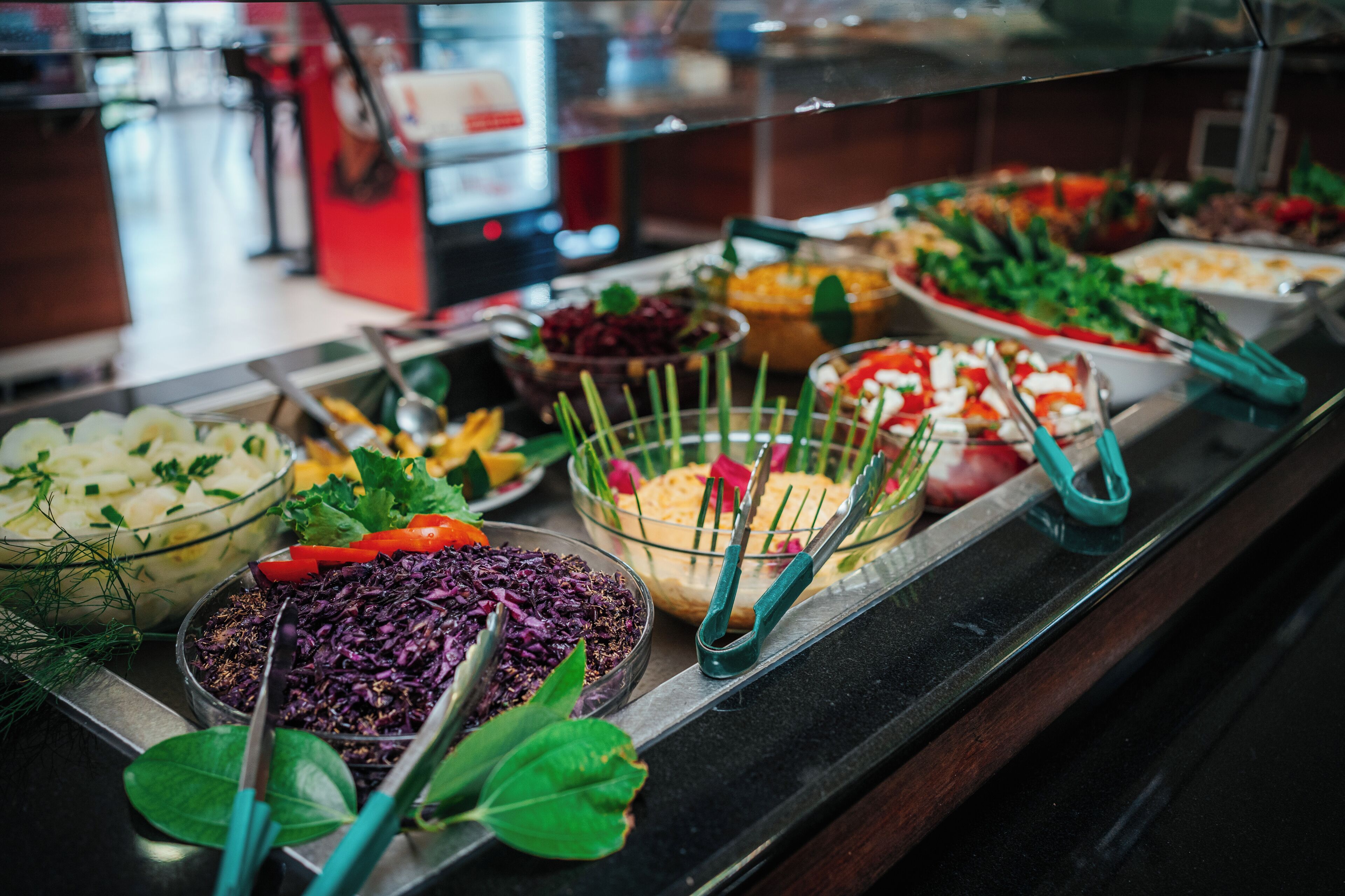 Un buffet con diversi piatti, tra cui insalate, verdure e altri cibi pronti.