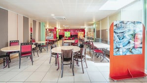 Interior de un restaurante con varias mesas y sillas, un llamativo letrero con motivos de pescado y un diseño de techo moderno y luminoso.