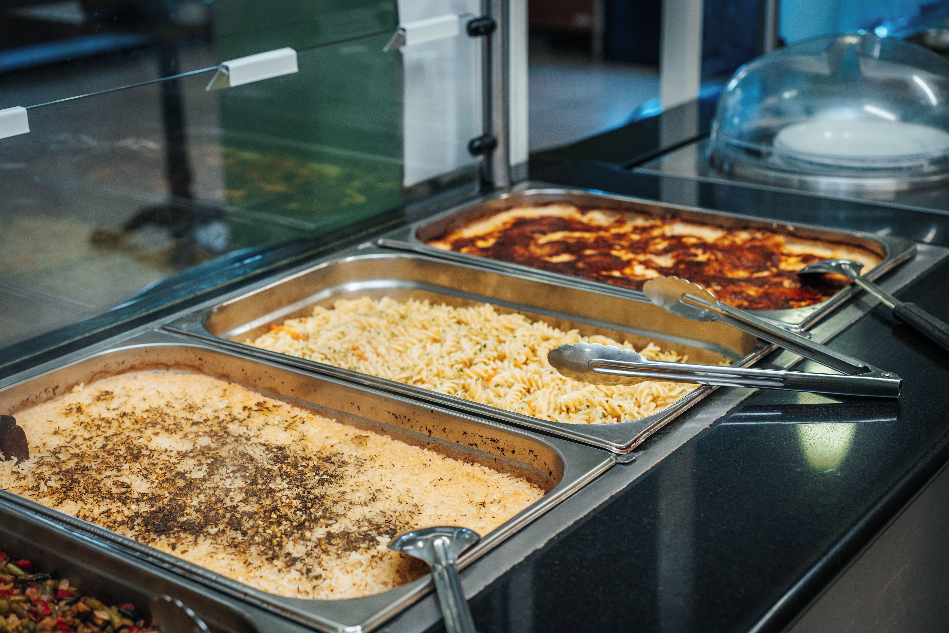 Un buffet proposant divers plats, notamment des pâtes, du riz et un gratin.