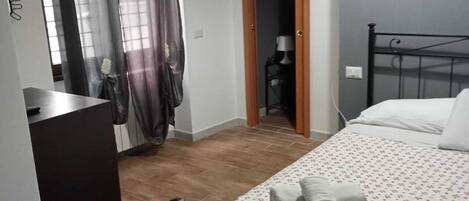 Un dormitorio con una cama, un escritorio y una puerta que da a otra habitación.
