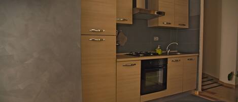 A modern kitchen with wooden cabinets, a stove, and a sink.
