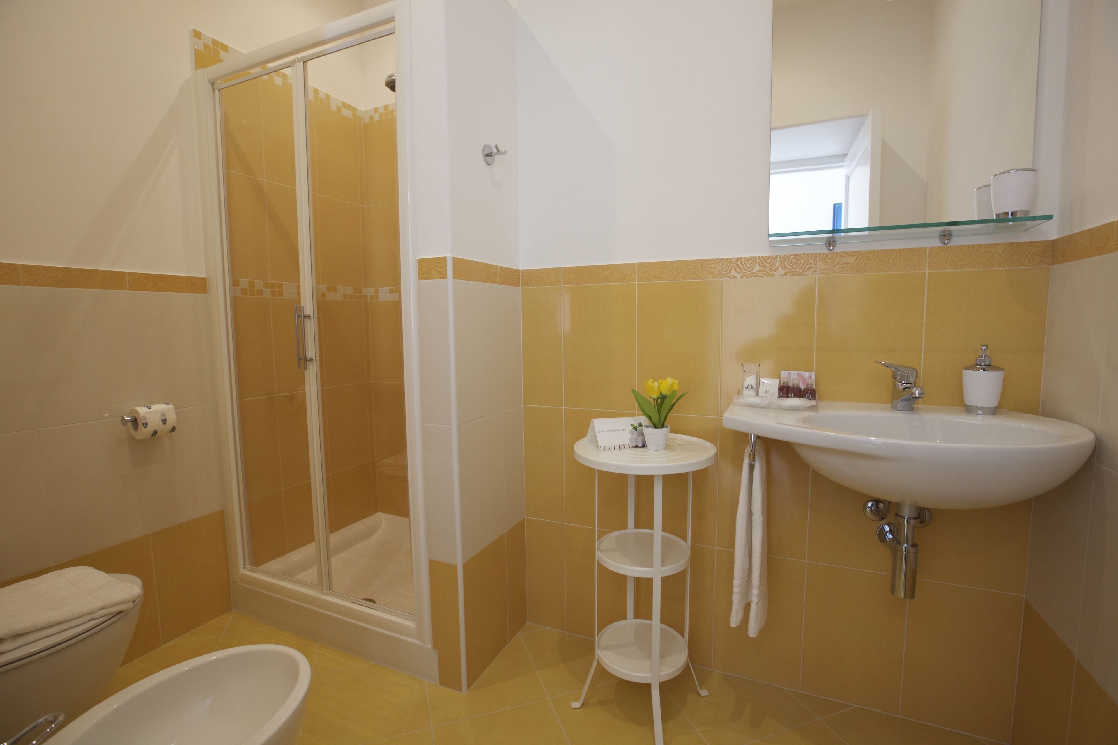 A bathroom with a shower, toilet, sink, and a small table with a plant.
