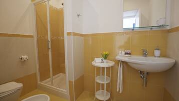 A bathroom with a shower, toilet, sink, and a small table with a plant.
