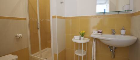 A bathroom with a shower, toilet, sink, and a small table with a plant.