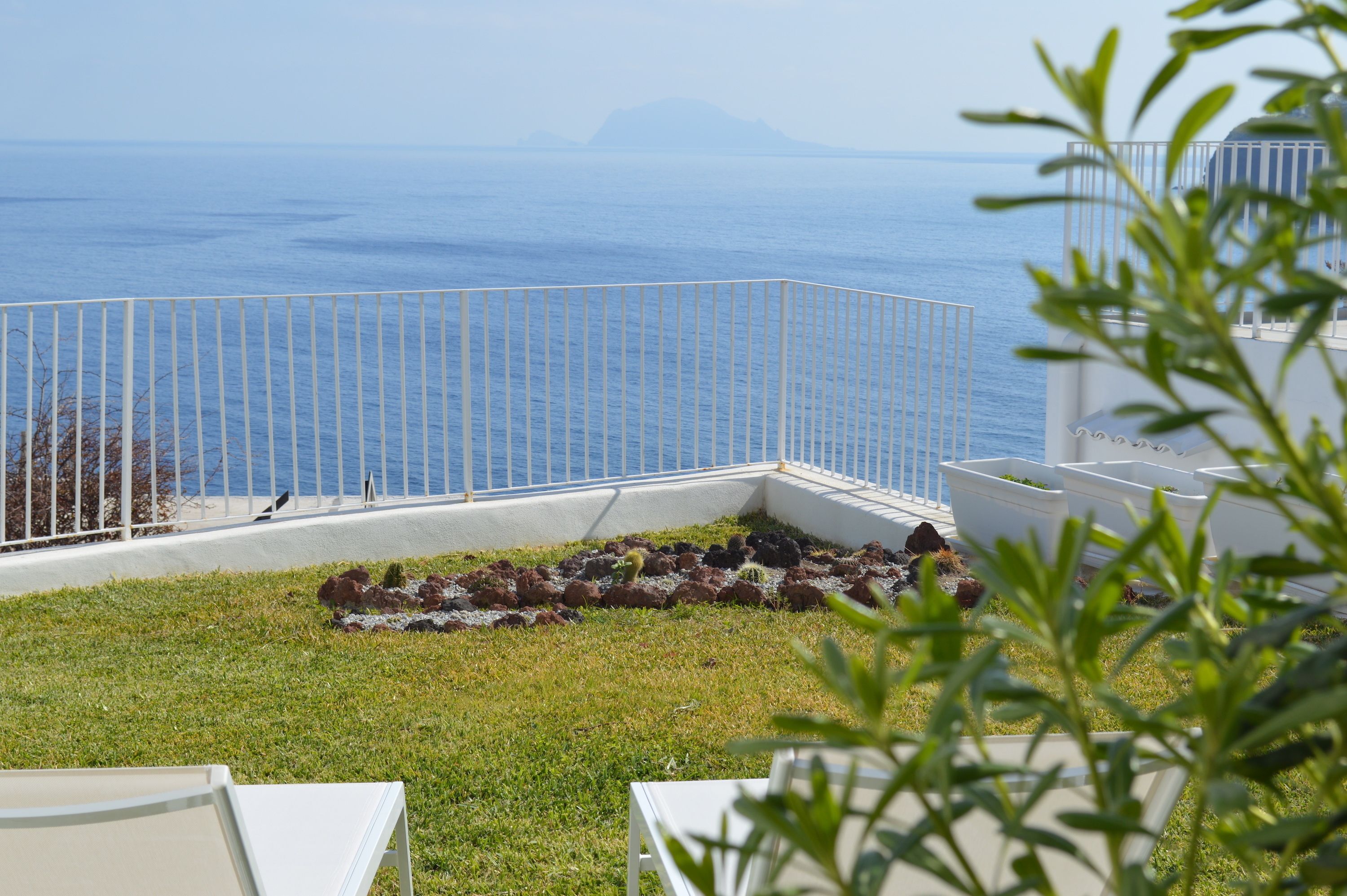 A coastal view with a white fence, a grassy area, and a body of water.