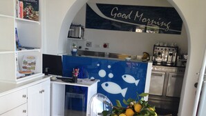 A modern kitchen with a breakfast table set with fruits and a coffee machine. - A Alera Room and Breakfast (Malfa)