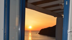 A room with a view of the sunset over the sea, a white door, and a small white bench. - A Alera Room and Breakfast (Malfa)