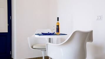 Een moderne eethoek met een witte tafel, een blauwe schaal, een wijnfles en een witte stoel.